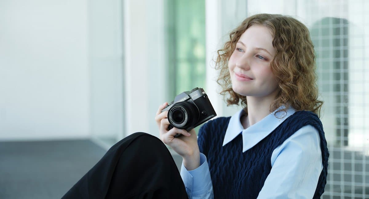 Cô gái cầm máy ảnh Fujifilm X-T30 III ngồi bên cửa sổ – làm quen máy trước khi cài đặt