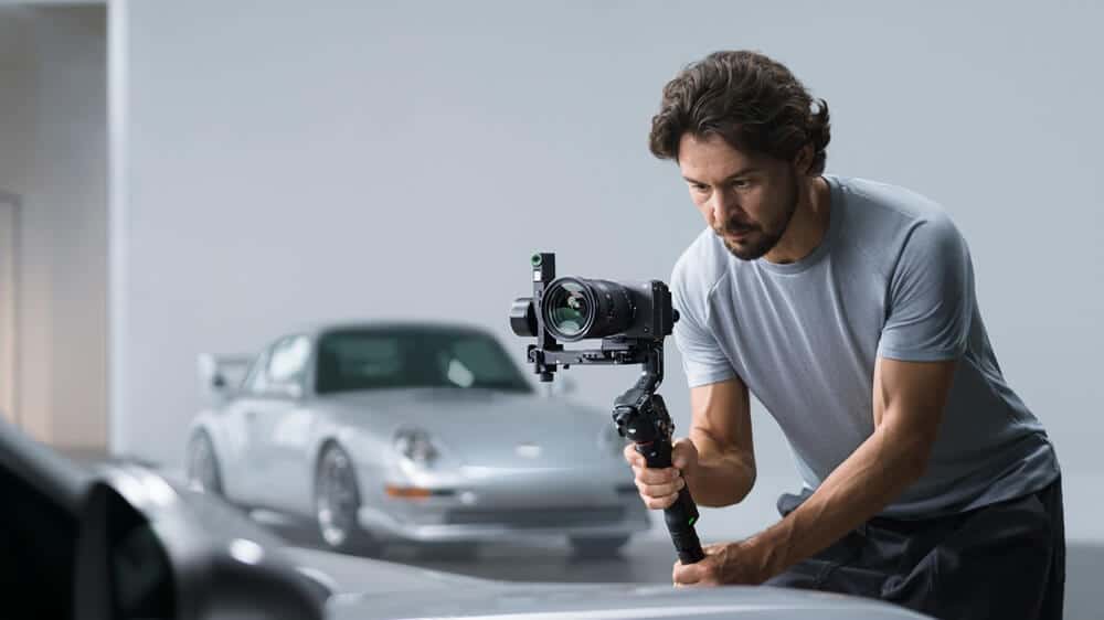 Người dùng cầm DJI RS 5 gắn máy ảnh quay cảnh xe ô tô